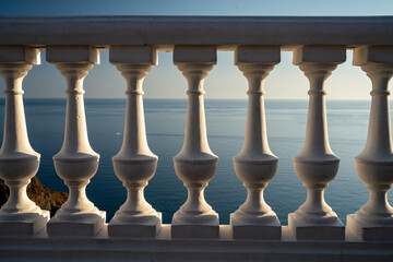 Classic balustrade on the embankment against the sea. White balcony over the sea. Promenade with a beautiful view of the sea on a clear day. Close-up of the balustrade by the sea