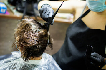 Hairdresser dyes woman hair. Hairdresser colorist dyes the hair of woman. Beautician, hand. Hairdressing during the coronavirus - obrazy, fototapety, plakaty