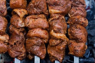 Raw meat on skewers is prepared on the grill