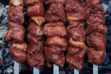 Raw meat on skewers is prepared on the grill