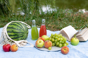 summer picnic with watermelon, fresh fruit and bottled drinks on a blanket. Relaxation on summer