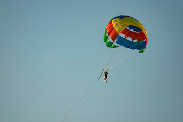 A man on a parachute parachuting over a blue lake.
