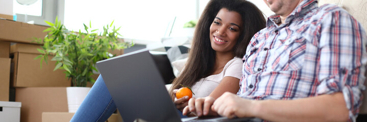 Portrait of wonderful afro-american woman with smiling man looking at laptop with gladness. Couple in love spending funny time together. Warm relations concept