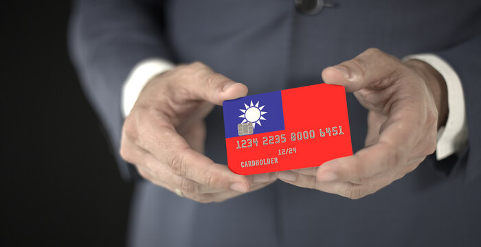 Businessman holds plastic bank card with printed flag of Taiwan, fictional numbers - Powered by Adobe