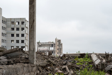 Destroyed large building with a pile of concrete debris and beams against the gray sky. Background