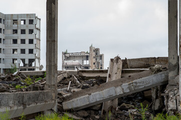 A large destroyed building with a pile of gray concrete debris and beams in the foreground. Background.