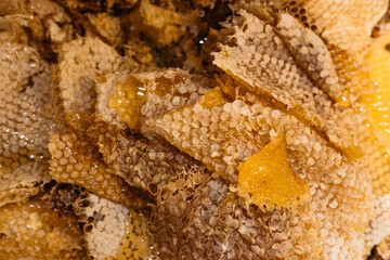 The texture of the honeycomb. Thin layers of honey lie in a pile. A lot of beeswax and honey on it, the remains after removing the honey from the frames of the hive. Beekeeping.