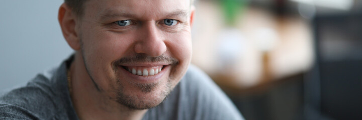 Close-up of smiling middle-aged man looking in camera. Cheerful attractive person dressed in grey shirt. Copy space in right side. Modeling and happiness concept
