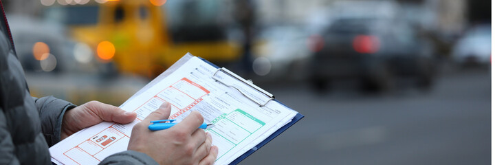 Close-up of male insurance agent filling report claim form on clipboard. Copy space in right side....