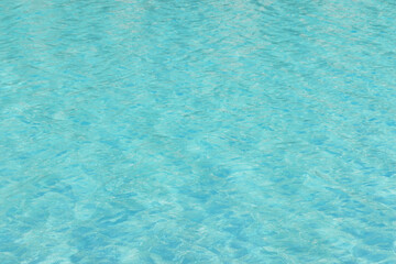 Blue swimming pool water texture reflecting the sun rippled