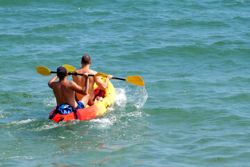 two young men are sailing on a kayak in the sea