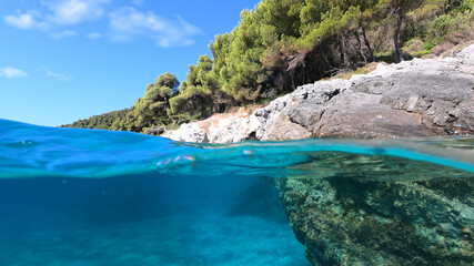 Underwater split line photo of beautiful caves with deep turquoise sea and Pine trees of Kastani...