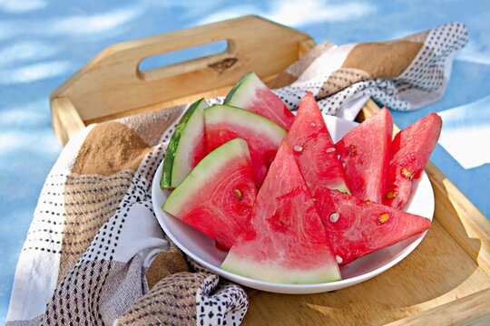 Sliced juicy watermelon on a white plate on a wooden tray. Summer concept. Summer snacks.