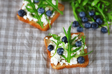 Selective focus. Cottage cheese toast with blueberries and arugula. The keto diet. Keto toast. Bruschetta with cottage cheese.