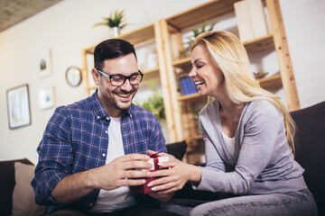 Happy couple with gift box at home celebrate Valentine's Day.