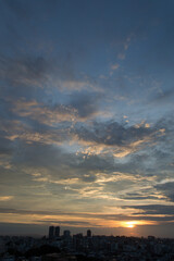 夕日でオレンジ色になった雲とシルエットの街並み