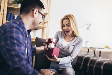 Happy couple with gift box at home celebrate Valentine's Day.