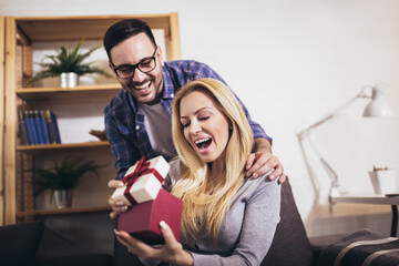 Happy couple with gift box at home celebrate Valentine's Day.