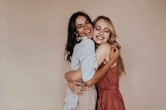 Pretty girls with trendy makeup embracing on light background. Excited caucasian sisters expressing love.