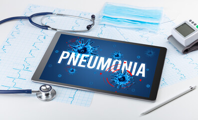 Tablet pc and doctor tools on white surface with PNEUMONIA inscription, pandemic concept