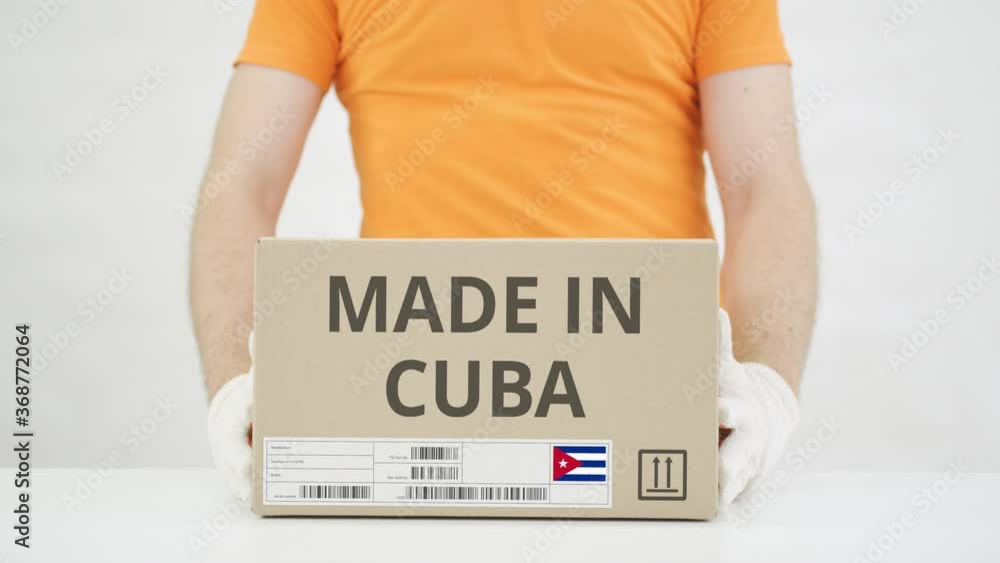 Aufkleber man puts cardboard box with made in cuba text on the table