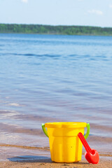 Children's toy bucket with a scoop on the sandy beach.