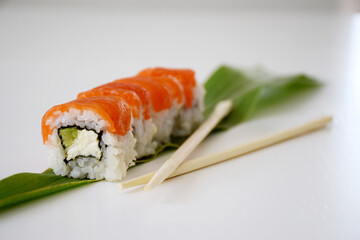 Philadelphia sushi with salmon, avocado and cheese on green leaf. Traditional Japanese food.