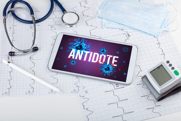 Tablet pc and doctor tools on white surface with ANTIDOTE inscription, pandemic concept