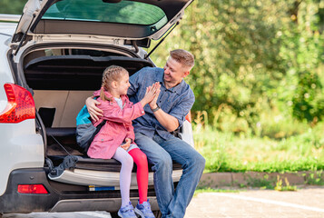 Father with daughter on trunk after schooling