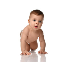 Cute little baby girl infant naked in diaper try to creep on floor smiling and looking aside isolated on white background