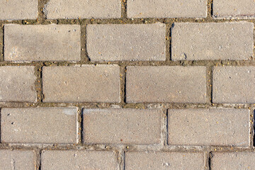 Gray stone tiles lies on the sidewalk. There are scratches on the stones in some places. Abstract textured background. Copy space for your text and decorations.