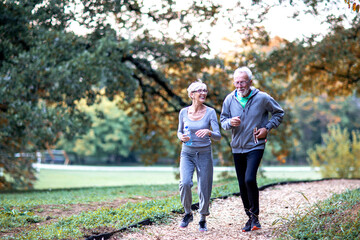 Obraz premium Aged couple jogging in the public park and smile