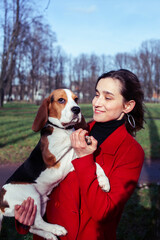 pretty young girl in redd coat playing with dog outside in green park, lifestyle people concept