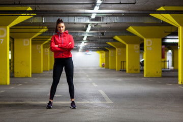 Obraz premium Fit girl in sportswear exercise in public garage to stay fit