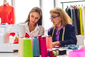 Portrait of woman fashion designer stylish sitting and working with color samples.Attractive woman working with mannequins standing and colorful fabrics at fashion studio