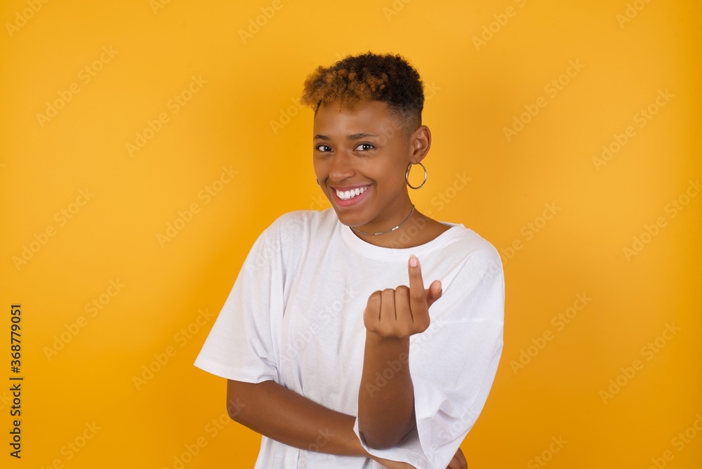 Sticker young african american girl with afro short hair wearing white tshirt standing over isolated yellow 