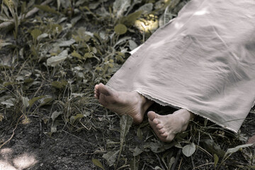 The human corpse is covered with a sheet. The victim of the crime lies in the forest.
