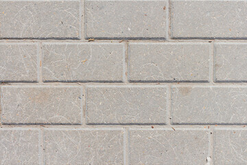 Gray stone tiles lies on the sidewalk. There are scratches on the stones in some places. Abstract textured background. Copy space for your text and decorations.