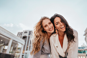 Ecstatic long-haired girls posing in spring day on sky background. Outdoor photo of two...