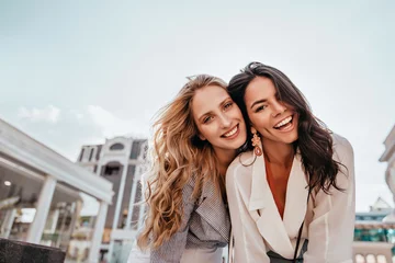 Fotobehang Ecstatic long-haired girls posing in spring day on sky background. Outdoor photo of two good-looking female friends. © Look!
