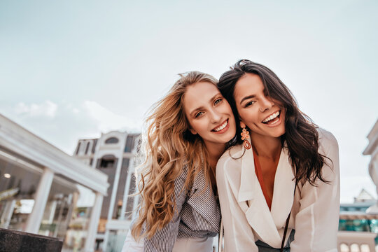 Ecstatic Long-haired Girls Posing In Spring Day On Sky Background. Outdoor Photo Of Two Good-looking Female Friends.