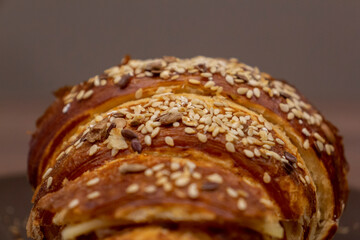 Close up view of tasty croissant sprinkled with sesame and made from puff pastry. Selective focus. Fresh pastry theme.