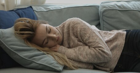 Young sleepy woman falling down on sofa at home.