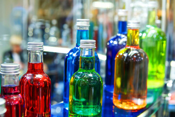 Glass bottles with colorful alcoholic products. Making alcoholic drinks at home. Close-up