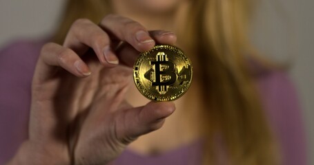 Woman showing gold bitcoin coin