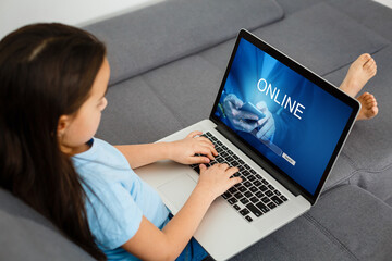 Cute little girl reacts with shock while using a laptop. Internet safety concept. Toned image with selective focus