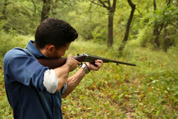 a man with a gun in a green forest