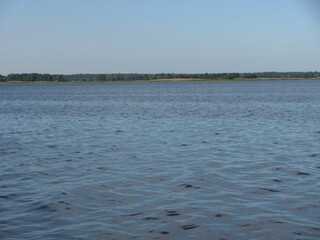 large water area with ripples and forest on the horizon