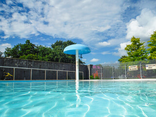 Beautiful outdoor swimming pool with umbrella sprinkler and transparent water 