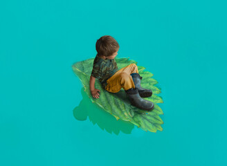 Baby swims on lake on a large green leaf
